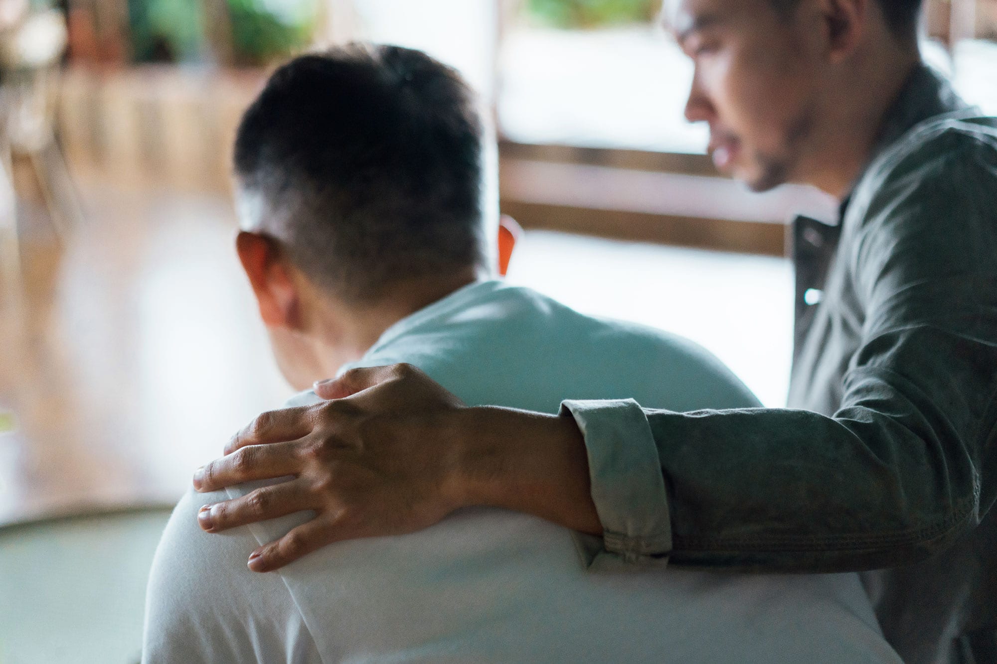 rear view of son and elderly father sitting together at home