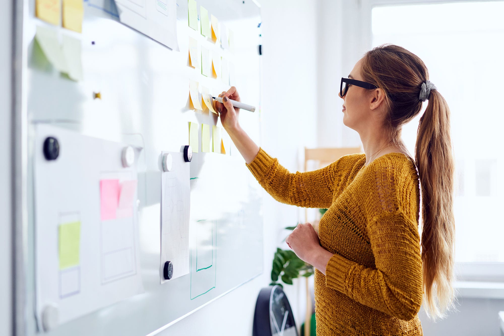 Young woman working in startup office writing on whiteboard
