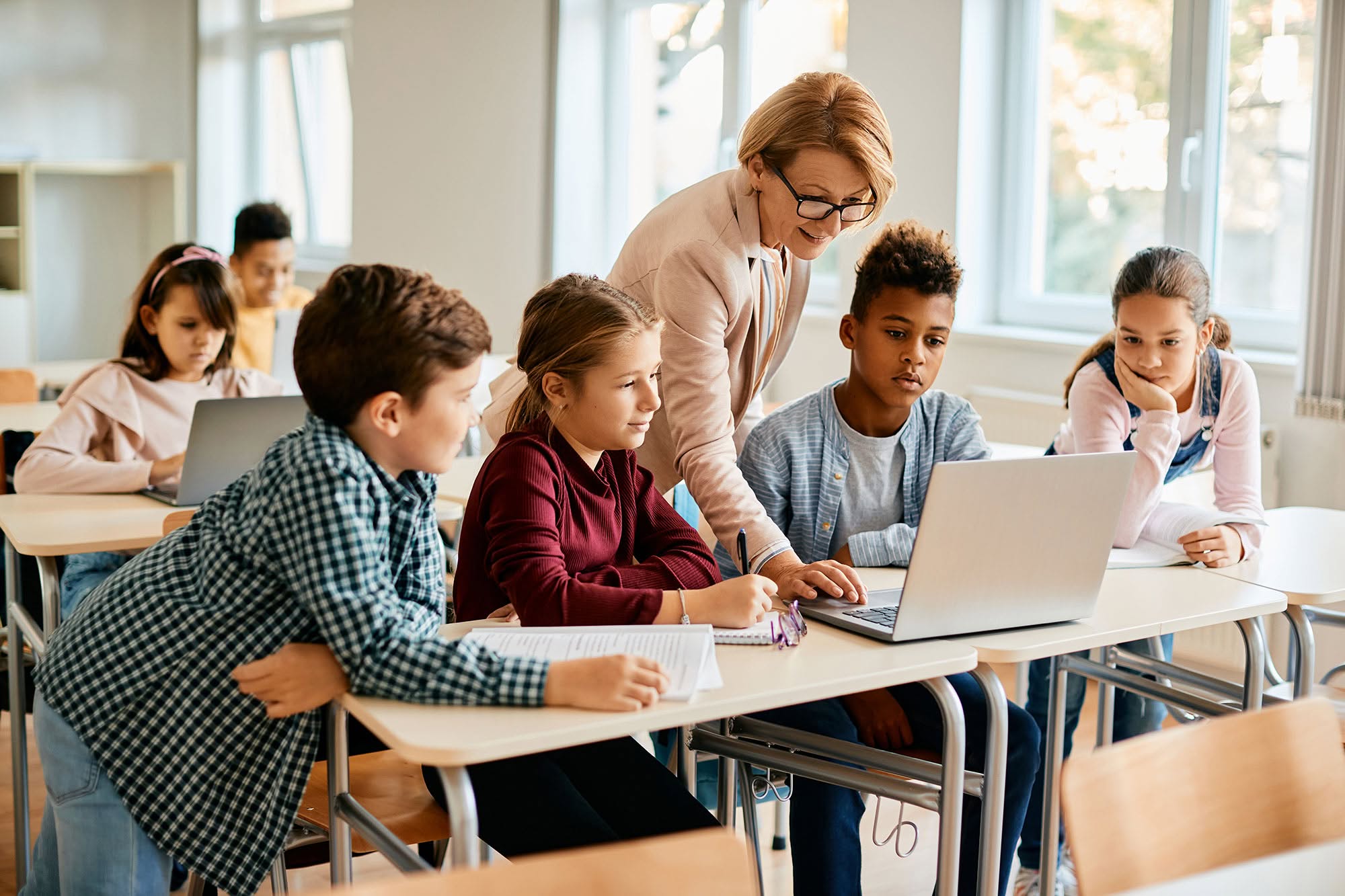 Group of elementary students having computer class with their teacher in the classroom